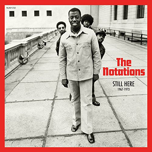 Four men stand on a paved terrace with red borders and text overlay.