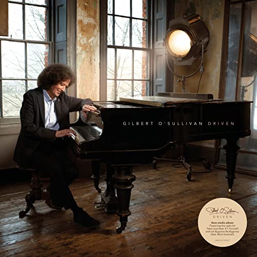 Gilbert O'Sullivan seated at a grand piano, album cover for "Driven".
