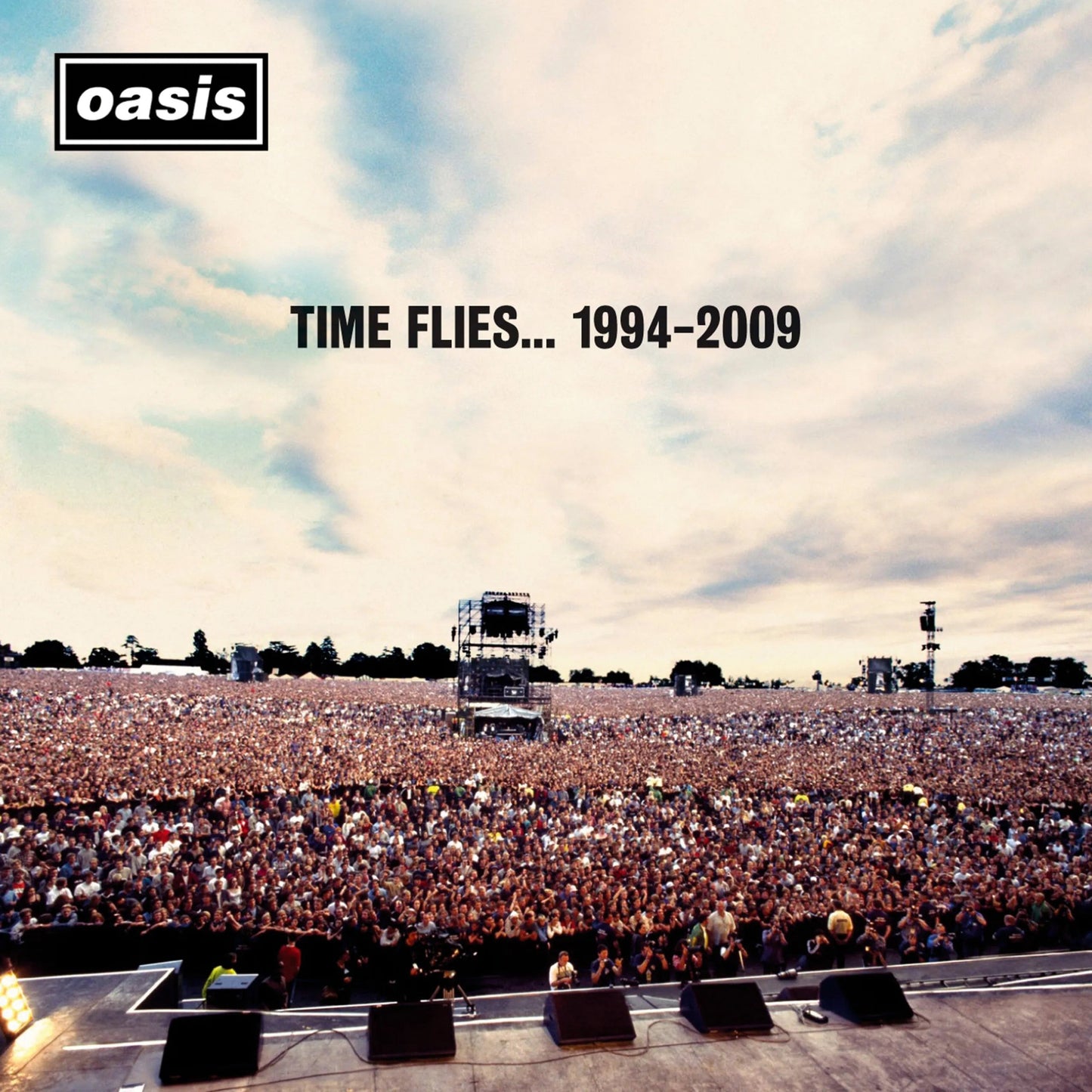 Oasis album cover: large concert crowd facing a stage under cloudy sky.