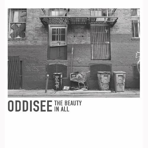 Black and white photo of a brick building exterior with trash cans and text.