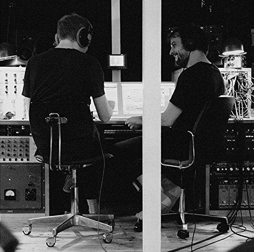 "Black-and-white image of two men working in a recording studio."