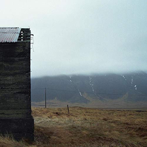 Weathered wooden building beside a misty, mountainous landscape.