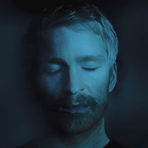 Close-up portrait of Ólafur Arnalds with eyes closed, blue lighting.