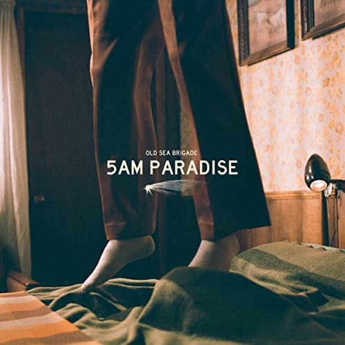 Album cover showing floating brown trousers over a bed in a dimly lit room.