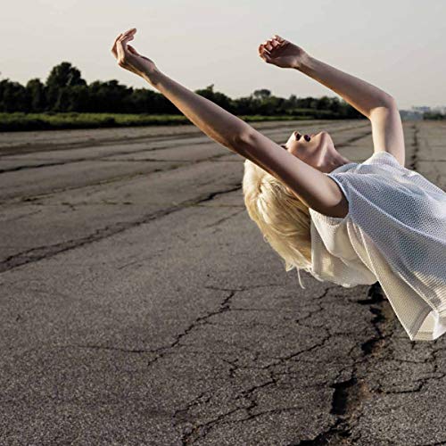 Woman with blonde hair appears to float above a cracked road.
