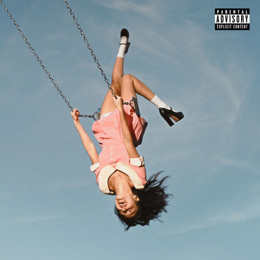A girl in a pink dress hanging upside down on a swing against blue sky.