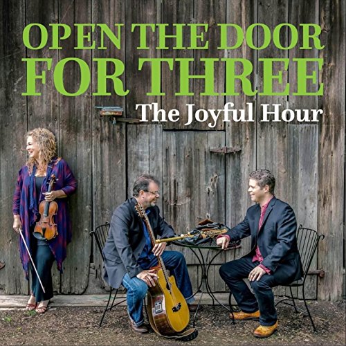 Three musicians with violin, cello, and guitar in front of a barn.