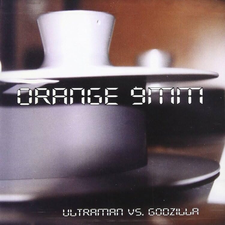 Orange vinyl record with “Ultraman vs. Godzilla” text and a coffee cup.
