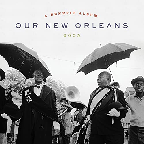 Black and white photo of a New Orleans brass band marching with umbrellas.