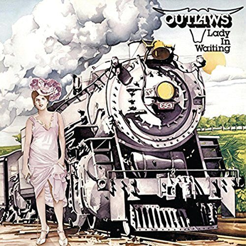 A woman in a pink dress stands before a large steam locomotive.