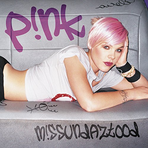 P!nk with pink hair lying on a gray couch with graffiti-style text.