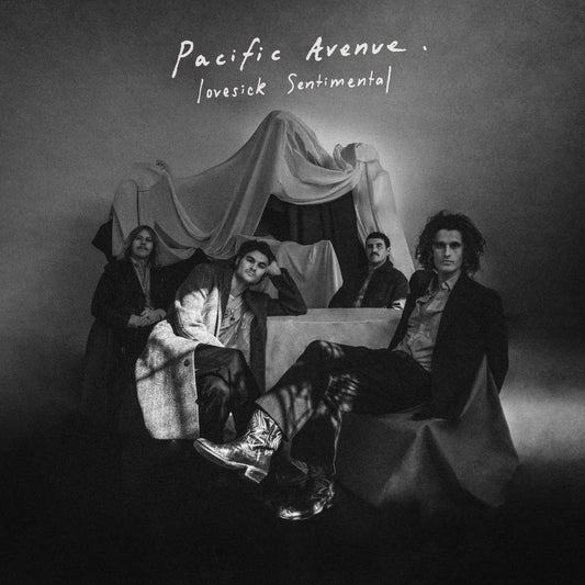 Black and white band portrait of four men posing with draped fabric and furniture.