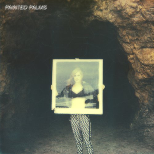 Album cover with a person holding a framed photo of a woman in a cave.