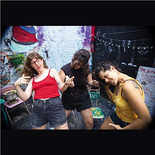 Three women posing playfully outdoors against a colorful, graffiti-covered wall.