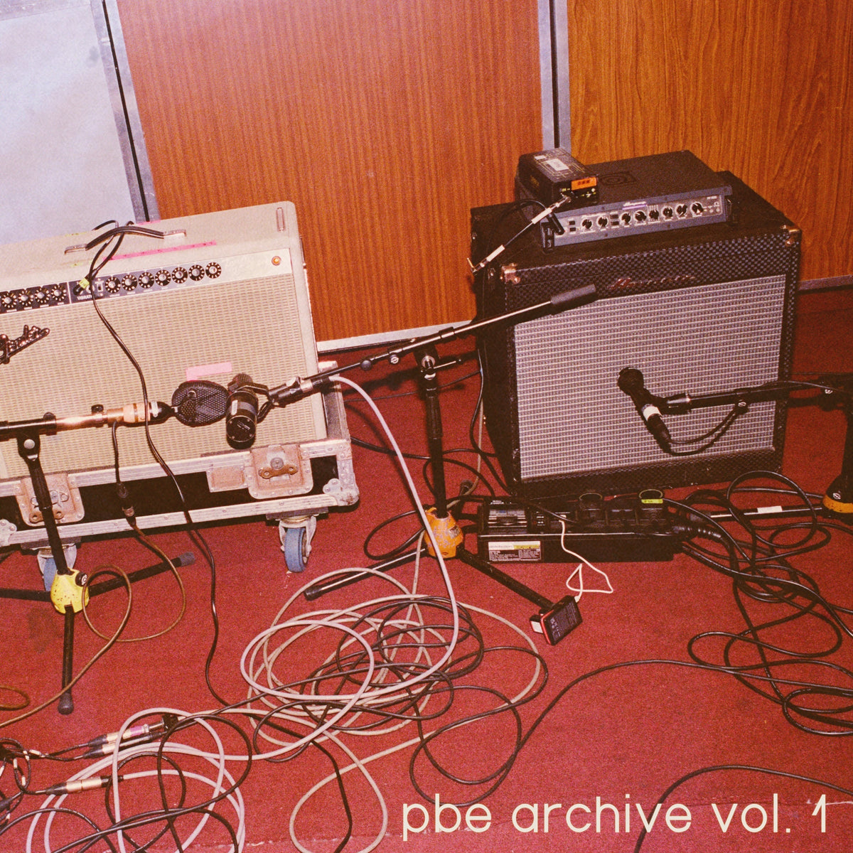 Vintage music equipment and cables on a red carpet; album art.
