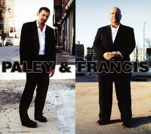 "Album cover featuring two men in suits standing on urban streets."