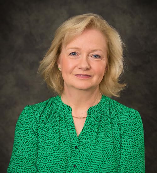 Portrait of a woman with blonde hair wearing a green top.