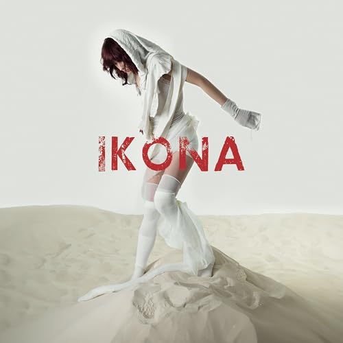 Woman in white clothing poses dramatically on a sandy dune, album art.