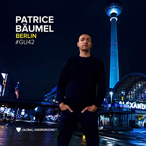 The image depicts a man standing in front of a cityscape at night. Alt text: Man standing in front of Berlin TV Tower at night.