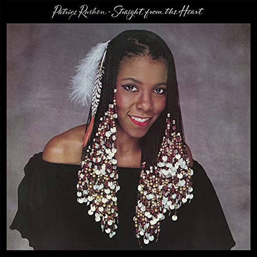 Patrice Rushen portrait with braided hair adorned with beads, feathers, and coins.