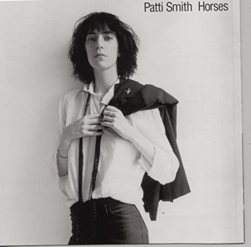 Black and white portrait of Patti Smith with a jacket draped over her shoulder.