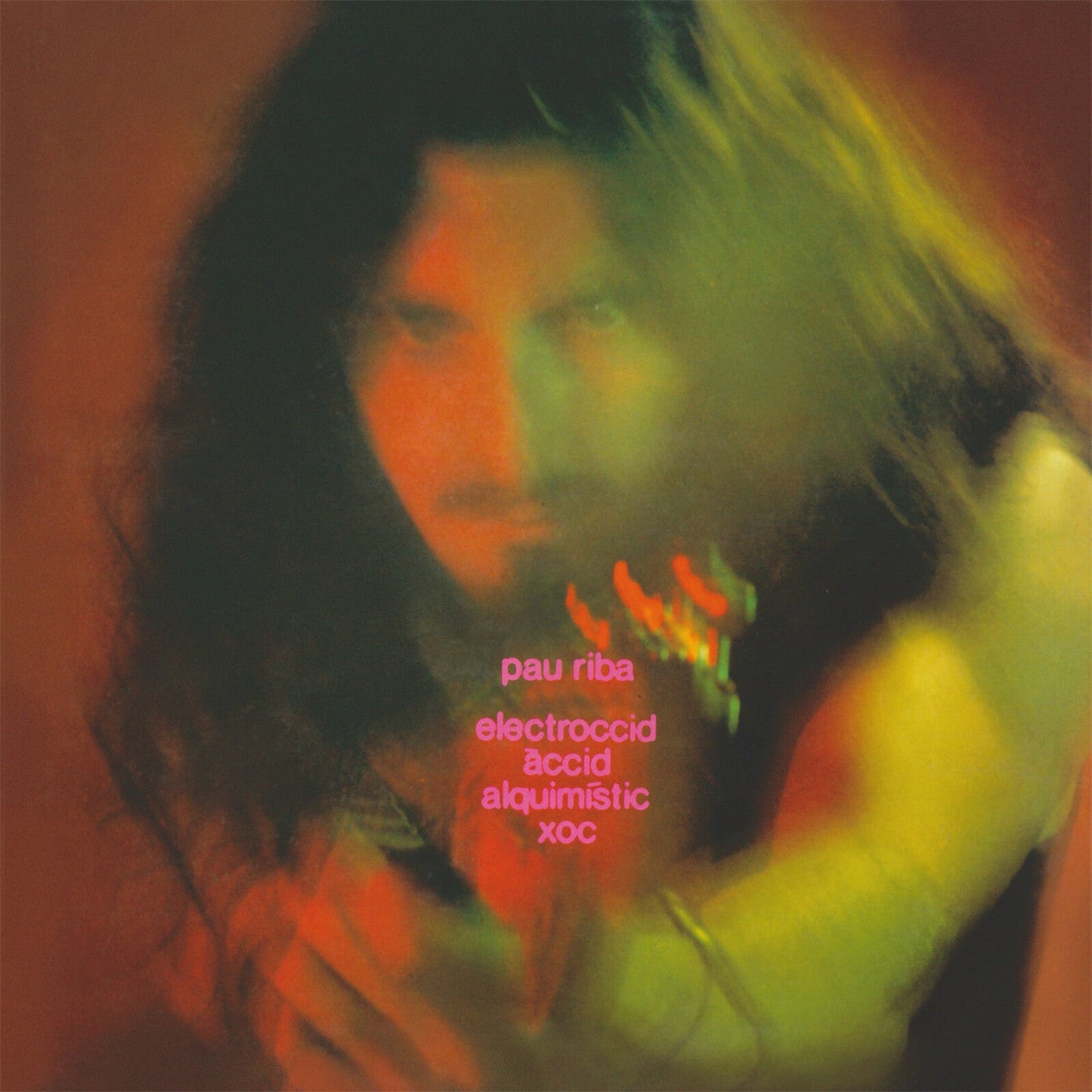 A blurry, warm-toned portrait of Pau Riba with pink text overlaying the image.