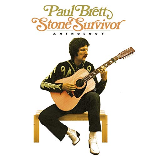 "Paul Brett sitting on a bench, playing an acoustic guitar, on a white background."