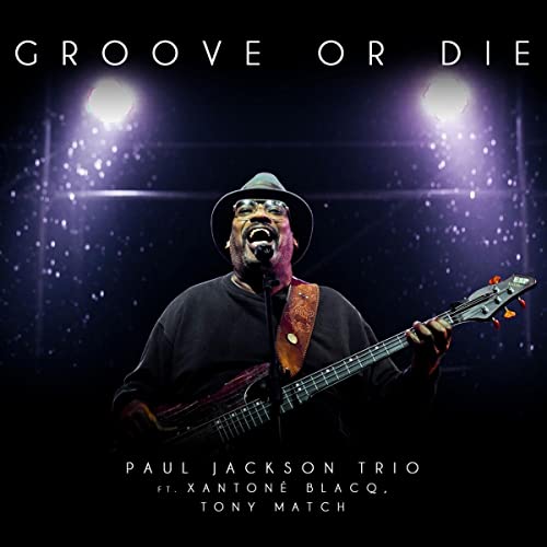 Paul Jackson playing bass guitar on album cover, stage lights behind.