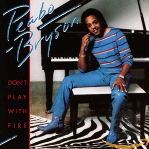 Peabo Bryson sits on a bench in front of a piano on a zebra rug.