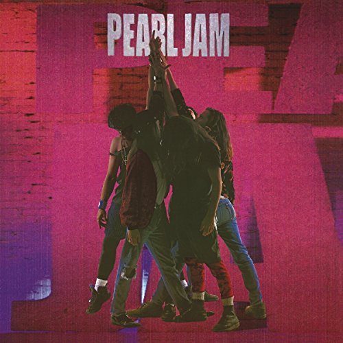 Five people stand in a circle with their arms raised against a pink wall.