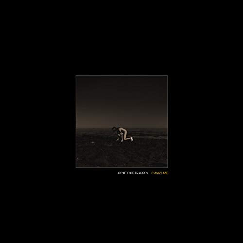 A person kneels on a dark, barren landscape under a dim, moody sky.