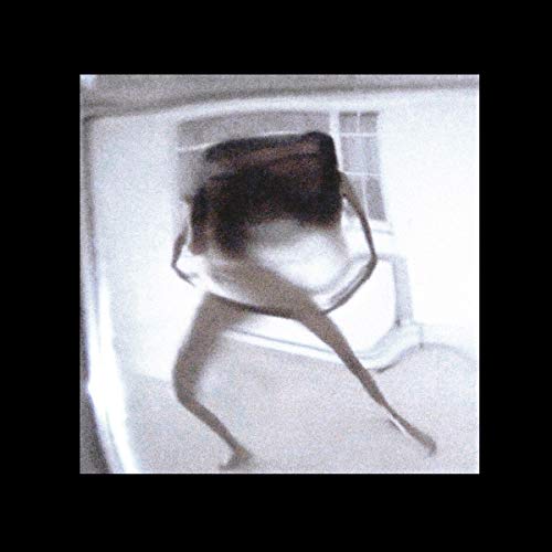 Blurry black and white photo of a person seated by a window.