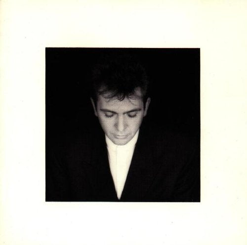 Black and white photo of a man in a dark suit against a dark background.