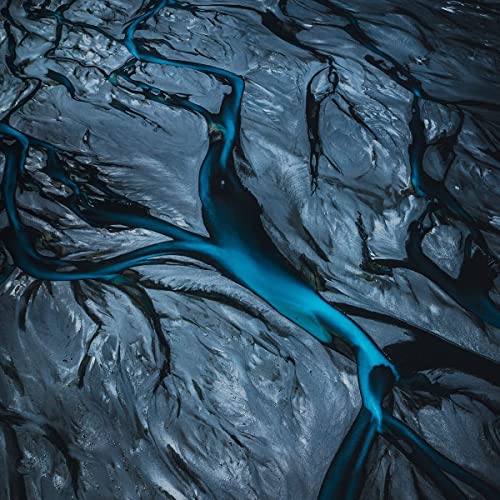 Aerial view of a dark, cracked landscape with bright blue streams.