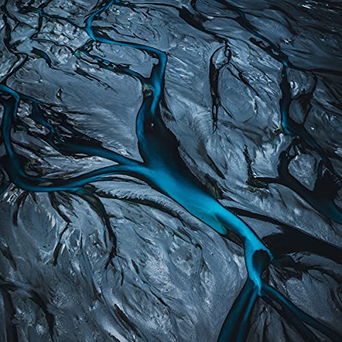 Aerial view of blue glacial river winding through dark, rocky terrain.