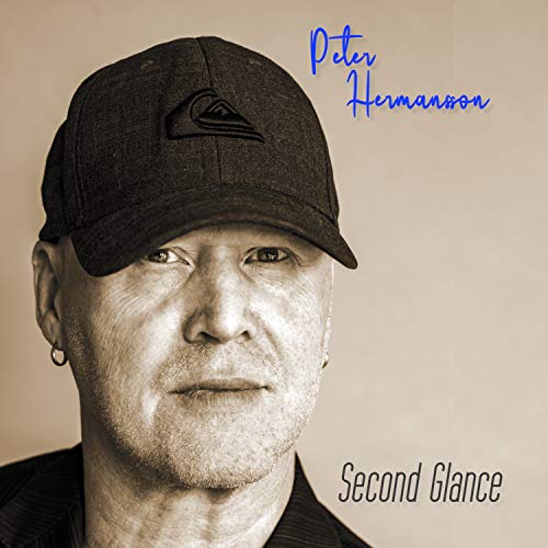 "CD cover featuring a man wearing a black cap, beige background, artist and album name."