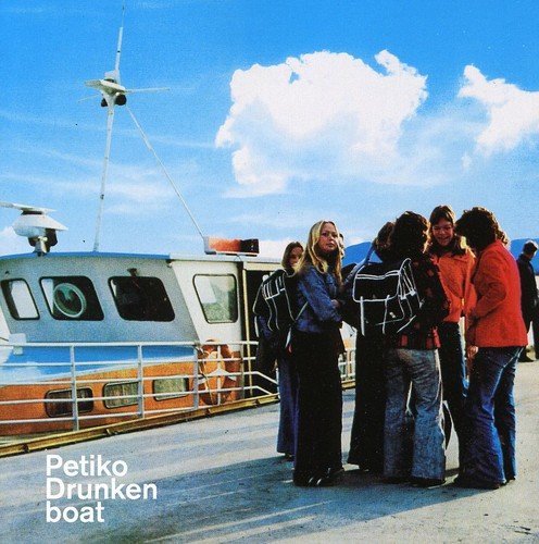 People gather near a ferry boat under a bright blue sky.