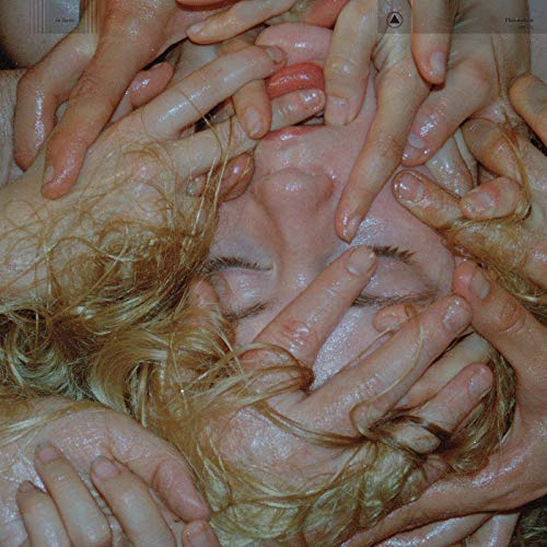Close-up of a face obscured by many overlapping hands.