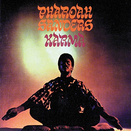 Pharoah Sanders sits in a meditative pose against a glowing, dark, atmospheric background.