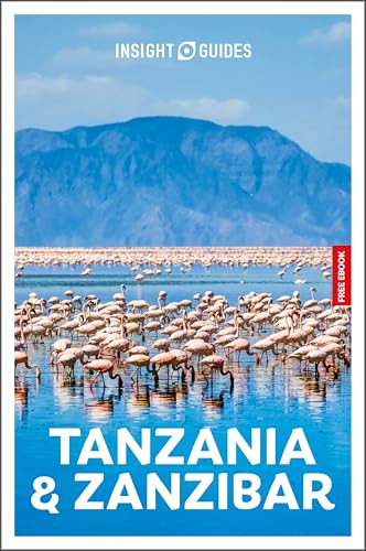 A large flock of flamingos in a lake with mountains in the background.
