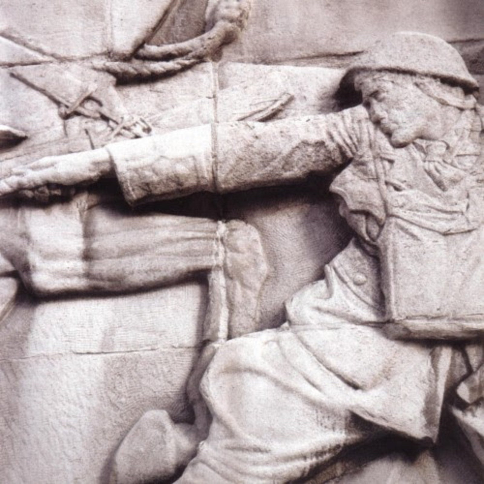 Stone relief sculpture of a soldier in uniform reaching forward with an outstretched arm.