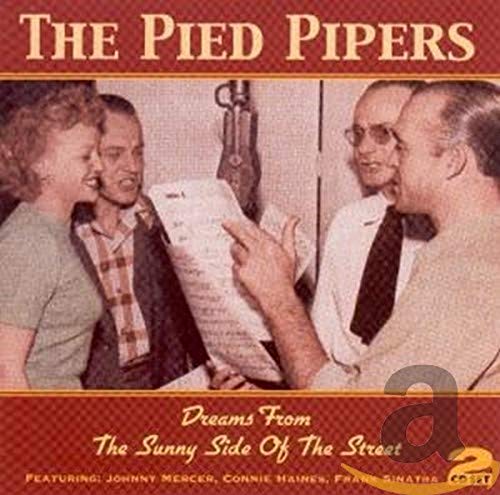 The Pied Pipers singing into a microphone while holding sheet music in a studio.