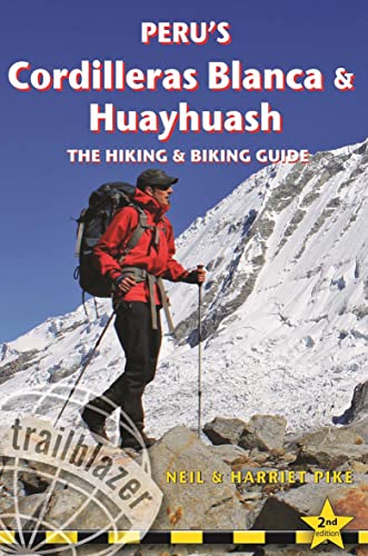 A hiker in a red jacket stands on a rocky mountain slope with snow.