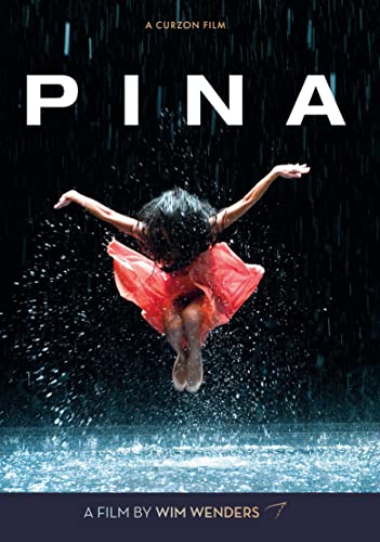 A dancer in a red dress leaps through rain against a black background.