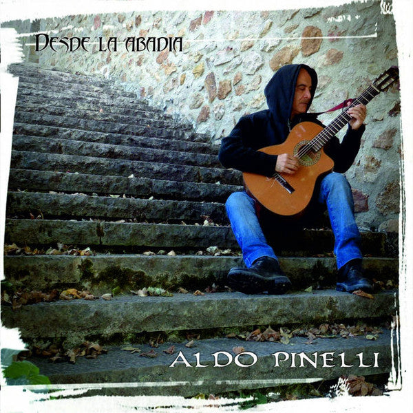 Man with guitar seated on stone steps, album cover art.
