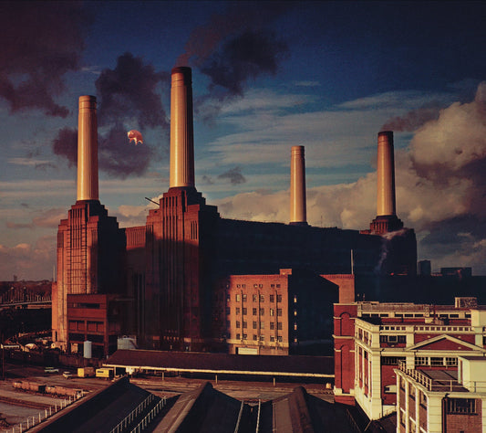 A large industrial power station with four tall chimneys and a floating pink pig.