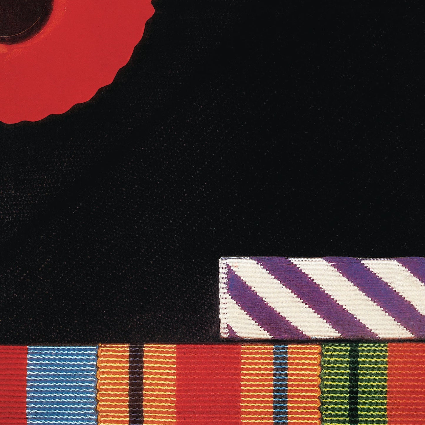 A red poppy and colorful military medal ribbons against a black background.