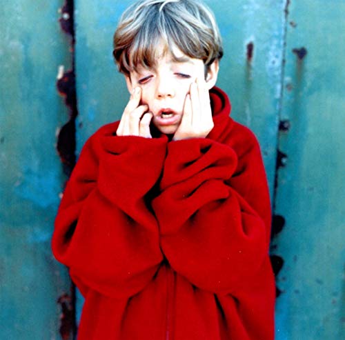 A young person in a red hooded sweatshirt pulling down their lower eyelids.