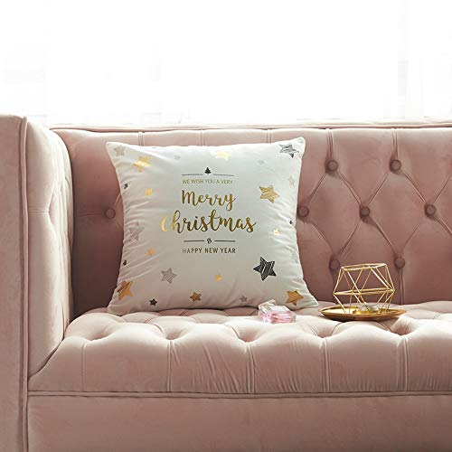 A white Christmas-themed throw pillow with gold stars sits on a pink tufted sofa.