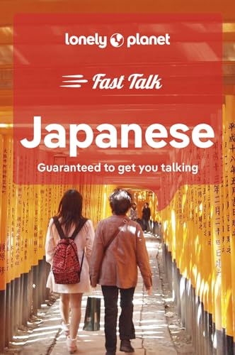 Two people walking through a path lined with bright orange Japanese torii gates.